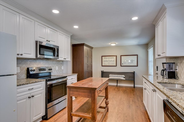 kitchen featuring stainless steel appliances, white cabinets, tasteful backsplash, light wood-type flooring, and recessed lighting