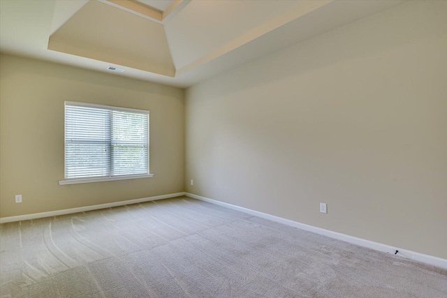 carpeted empty room featuring a tray ceiling