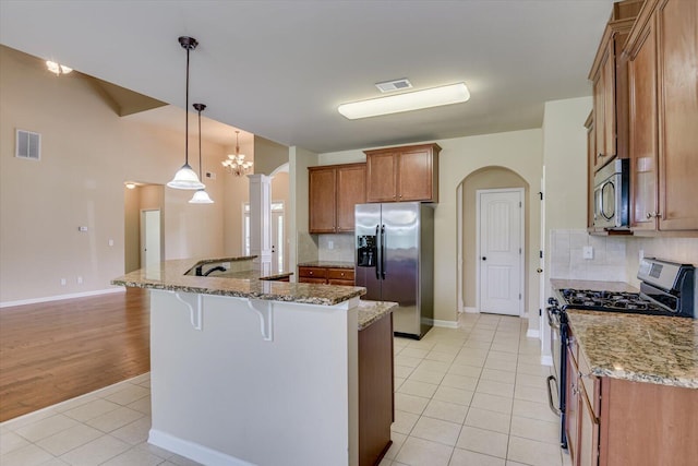 kitchen with decorative light fixtures, decorative backsplash, light tile patterned floors, and stainless steel appliances