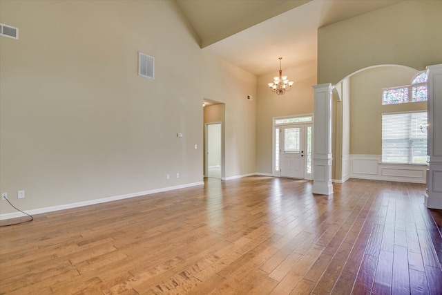 interior space featuring ornate columns, an inviting chandelier, a high ceiling, light hardwood / wood-style floors, and plenty of natural light