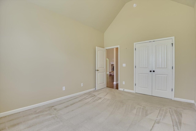 unfurnished bedroom featuring light colored carpet, high vaulted ceiling, and a closet