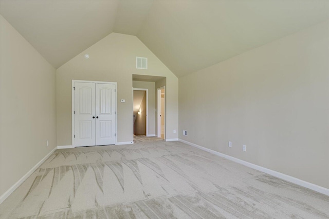 unfurnished bedroom with light carpet, vaulted ceiling, and a closet