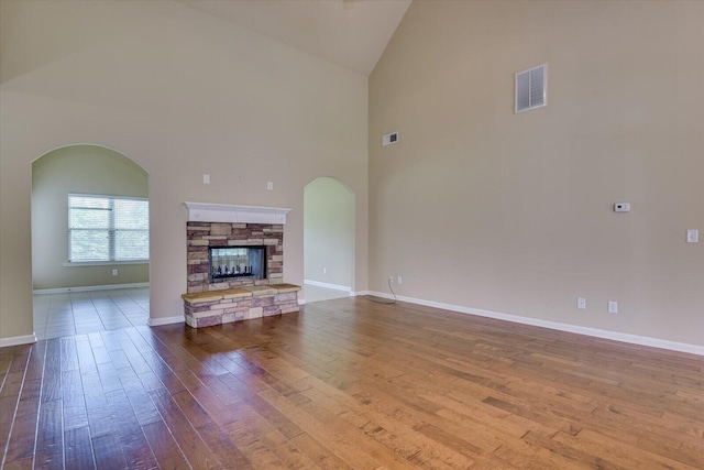 unfurnished living room featuring a fireplace, high vaulted ceiling, and wood-type flooring