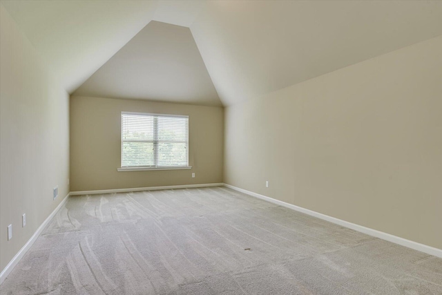 spare room with light colored carpet and vaulted ceiling