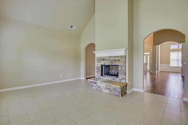 unfurnished living room featuring a towering ceiling, a fireplace, and light tile patterned flooring