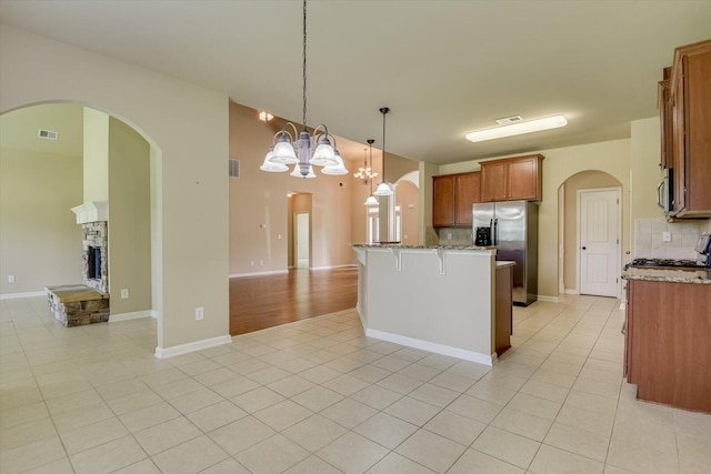 kitchen with appliances with stainless steel finishes, backsplash, light tile patterned floors, decorative light fixtures, and a chandelier