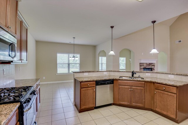 kitchen with backsplash, light stone counters, stainless steel appliances, sink, and hanging light fixtures