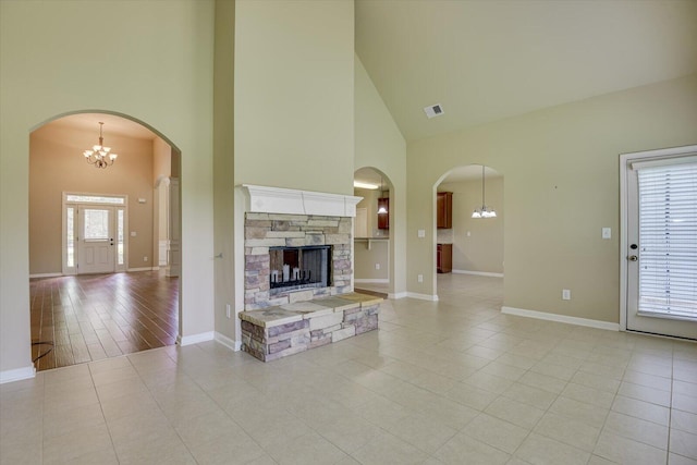 unfurnished living room with light tile patterned floors, a towering ceiling, and a stone fireplace