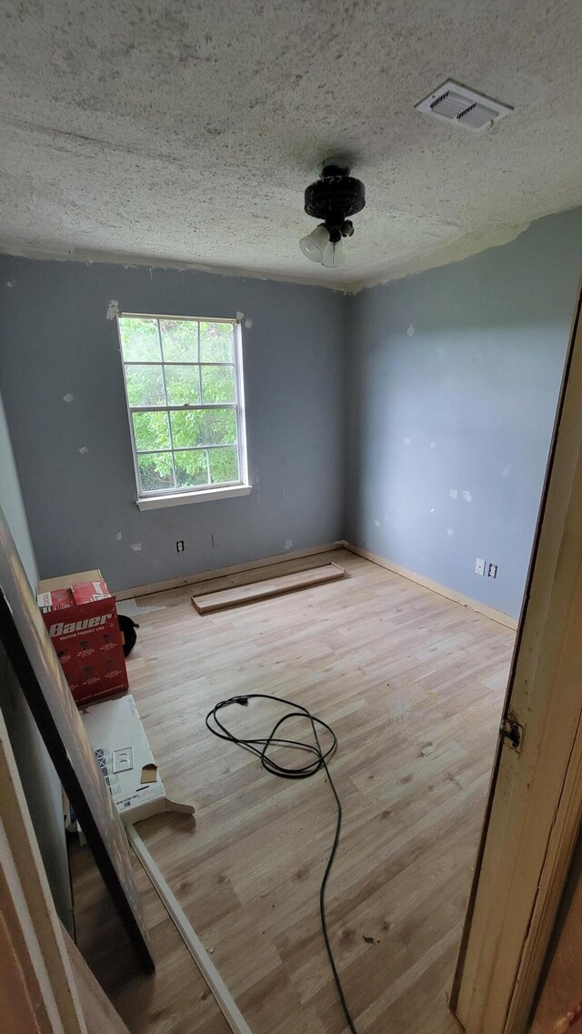 unfurnished room with a textured ceiling and light wood-type flooring