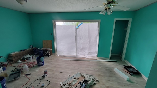 unfurnished room featuring a textured ceiling, light wood-type flooring, and ceiling fan