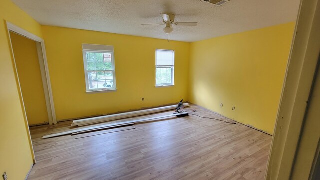 empty room featuring ceiling fan, light hardwood / wood-style floors, and a textured ceiling