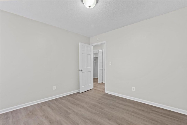 empty room with a textured ceiling and light wood-type flooring