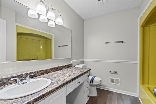 full bathroom featuring a textured ceiling, hardwood / wood-style flooring, toilet, independent shower and bath, and vanity