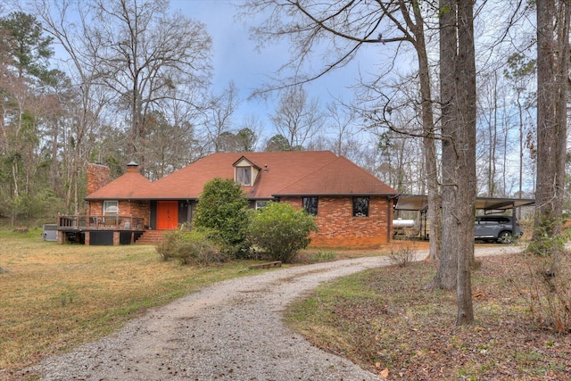 view of front of property with a front lawn, driveway, a wooden deck, a carport, and a chimney