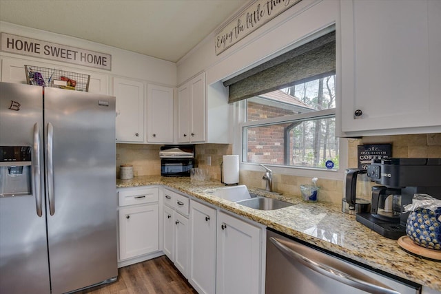 kitchen with a sink, decorative backsplash, appliances with stainless steel finishes, white cabinets, and dark wood-style flooring