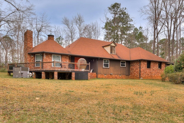 rear view of property featuring a wooden deck, a lawn, roof with shingles, and a chimney