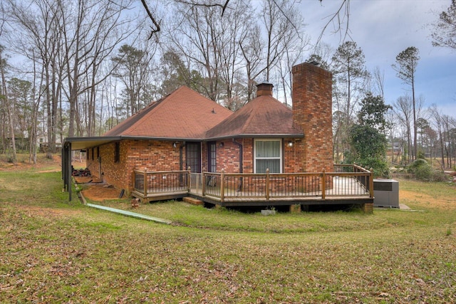 rear view of property featuring a wooden deck, central AC, a chimney, a lawn, and brick siding