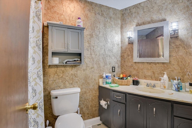 bathroom featuring toilet, wallpapered walls, and vanity