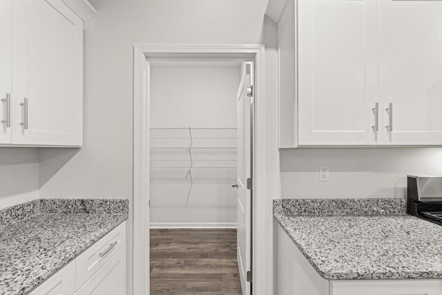 kitchen featuring dark hardwood / wood-style flooring, white cabinetry, and light stone counters