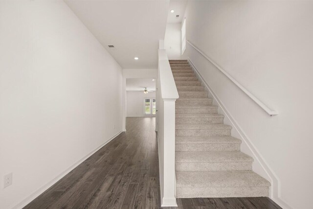 staircase with hardwood / wood-style floors and ceiling fan