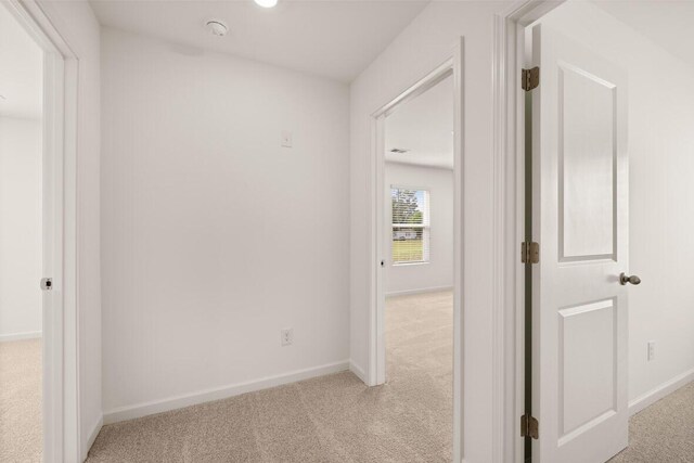 corridor featuring light colored carpet