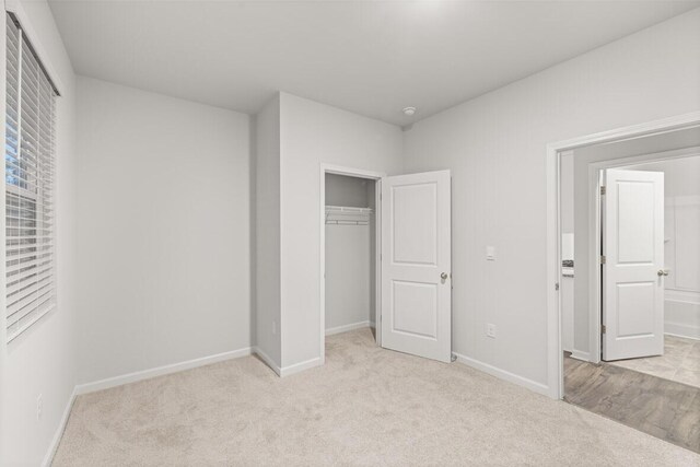 unfurnished bedroom with light colored carpet and a closet