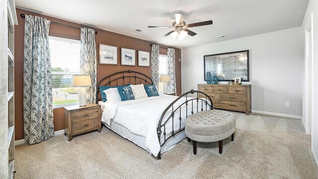 bedroom with light colored carpet, multiple windows, and ceiling fan