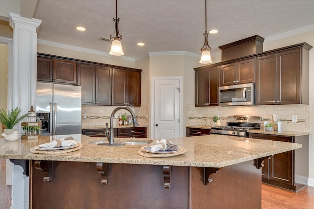 kitchen with appliances with stainless steel finishes, a sink, dark brown cabinets, light stone countertops, and recessed lighting