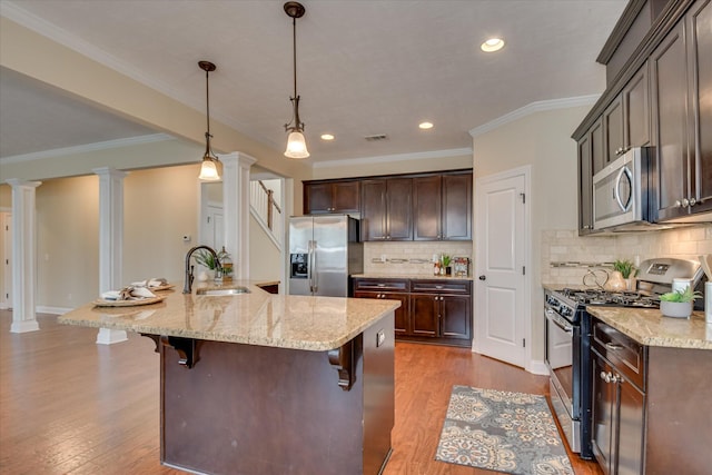 kitchen with stainless steel appliances, a sink, decorative columns, dark wood-style floors, and recessed lighting