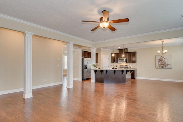 unfurnished living room with ceiling fan, a sink, ornate columns, dark wood-style floors, and crown molding