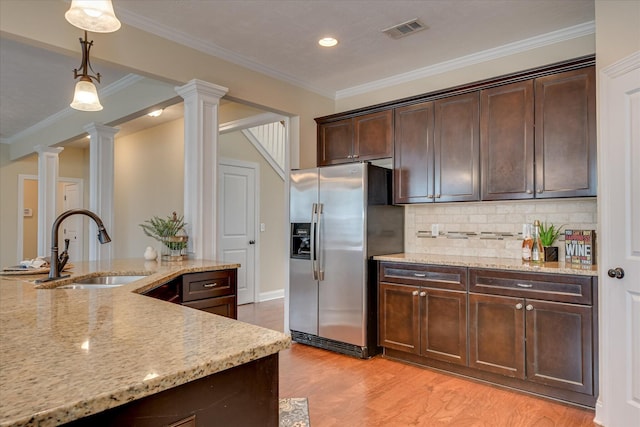 kitchen featuring stainless steel fridge with ice dispenser, a sink, ornate columns, dark brown cabinetry, and recessed lighting