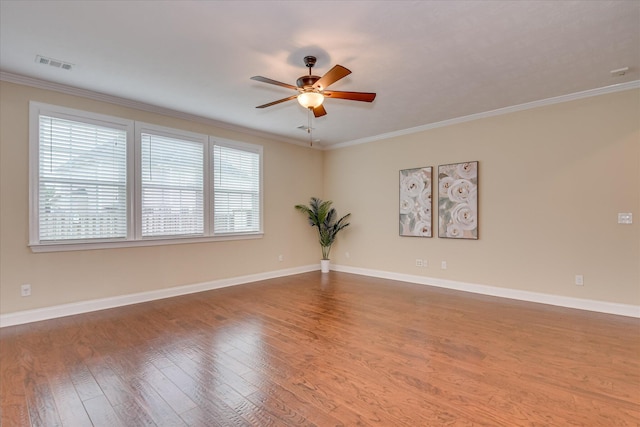 empty room with ceiling fan, ornamental molding, wood finished floors, and baseboards