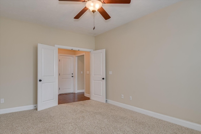 carpeted empty room with a ceiling fan and baseboards