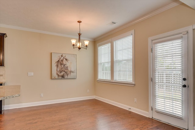 unfurnished dining area with crown molding, wood finished floors, a chandelier, and baseboards