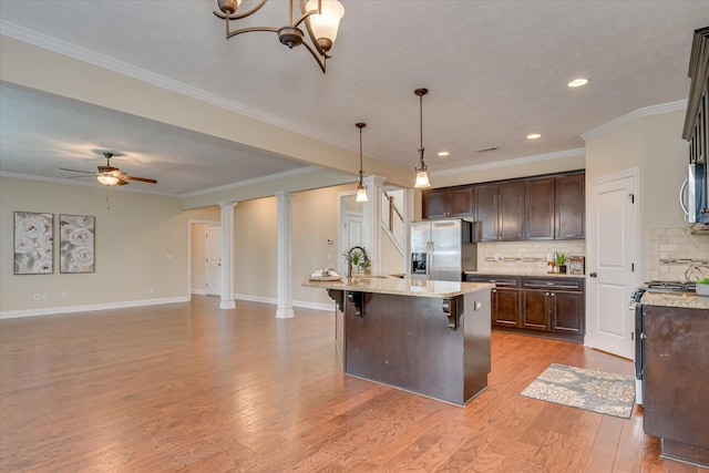 kitchen with stainless steel appliances, dark brown cabinetry, decorative backsplash, a ceiling fan, and a sink