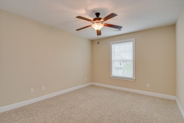 carpeted spare room featuring baseboards and a ceiling fan