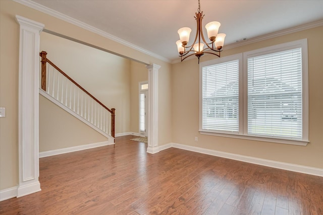 empty room with wood finished floors, a chandelier, baseboards, and ornamental molding