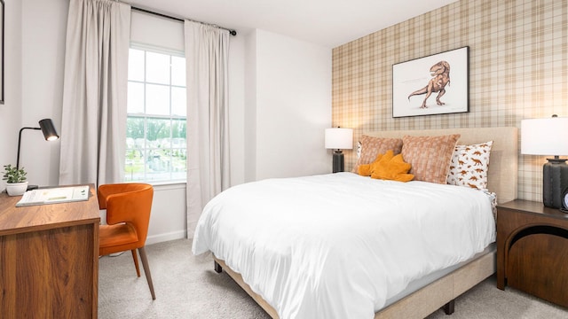 bedroom featuring wallpapered walls, an accent wall, baseboards, and light colored carpet