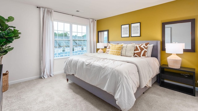 bedroom with baseboards, visible vents, and light colored carpet