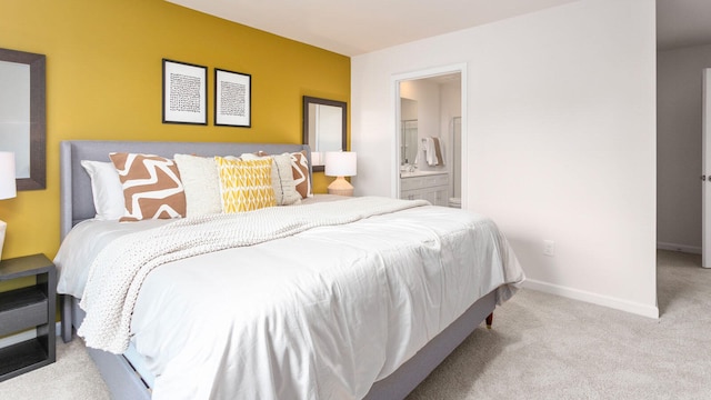 bedroom with baseboards, connected bathroom, and light colored carpet