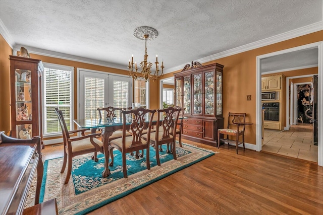 3974 Bolton St, Augusta, GA 30909 - dining area featuring a chandelier, crown molding, a textured ceiling, baseboards, and wood finished floors