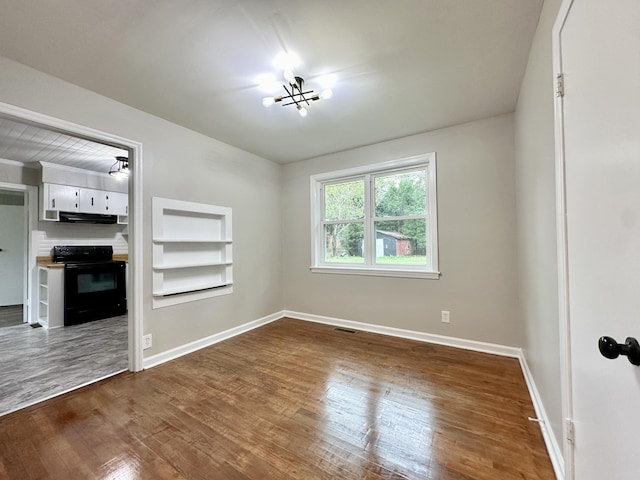 interior space with built in shelves, a chandelier, and hardwood / wood-style flooring