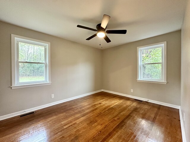 empty room with hardwood / wood-style floors, ceiling fan, and a healthy amount of sunlight