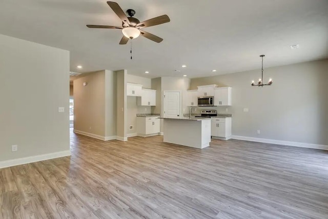 kitchen featuring pendant lighting, an island with sink, appliances with stainless steel finishes, light hardwood / wood-style floors, and white cabinetry