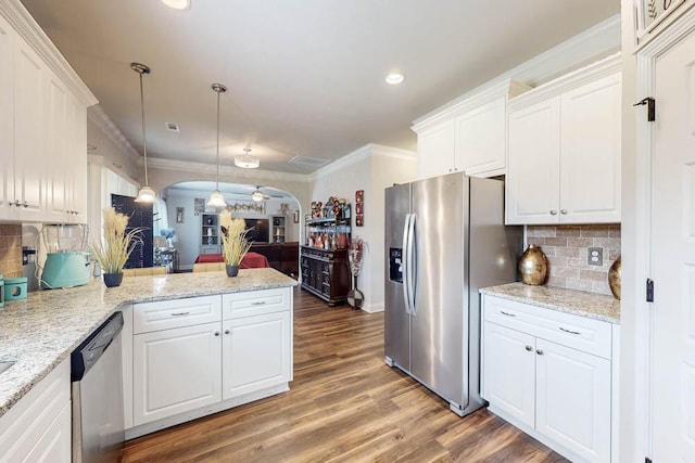 kitchen featuring decorative backsplash, hardwood / wood-style flooring, hanging light fixtures, appliances with stainless steel finishes, and white cabinets