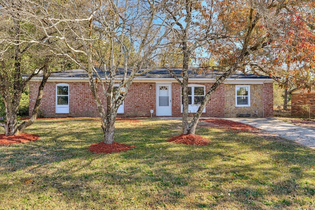 ranch-style home featuring brick siding, concrete driveway, and a front yard