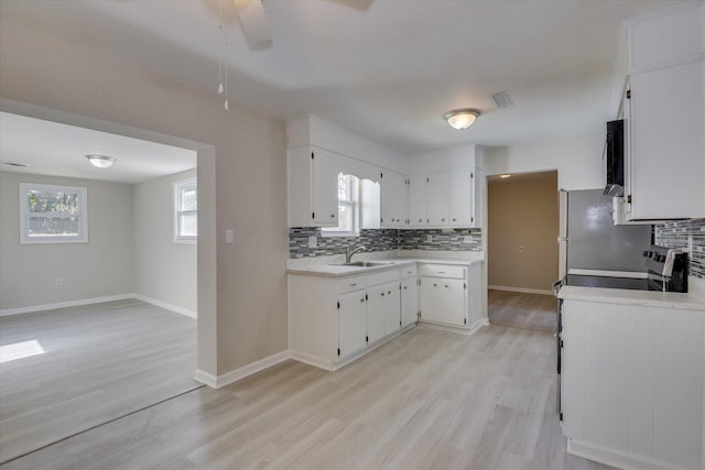 kitchen featuring a sink, white cabinetry, light wood-style floors, light countertops, and decorative backsplash