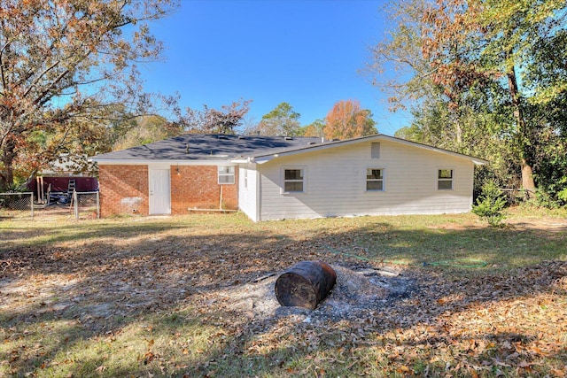 rear view of property featuring a yard, fence, and brick siding