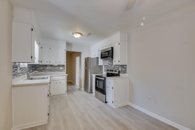 kitchen with stainless steel appliances, white cabinets, light countertops, and a sink