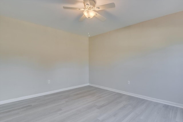 spare room featuring a ceiling fan, light wood finished floors, and baseboards